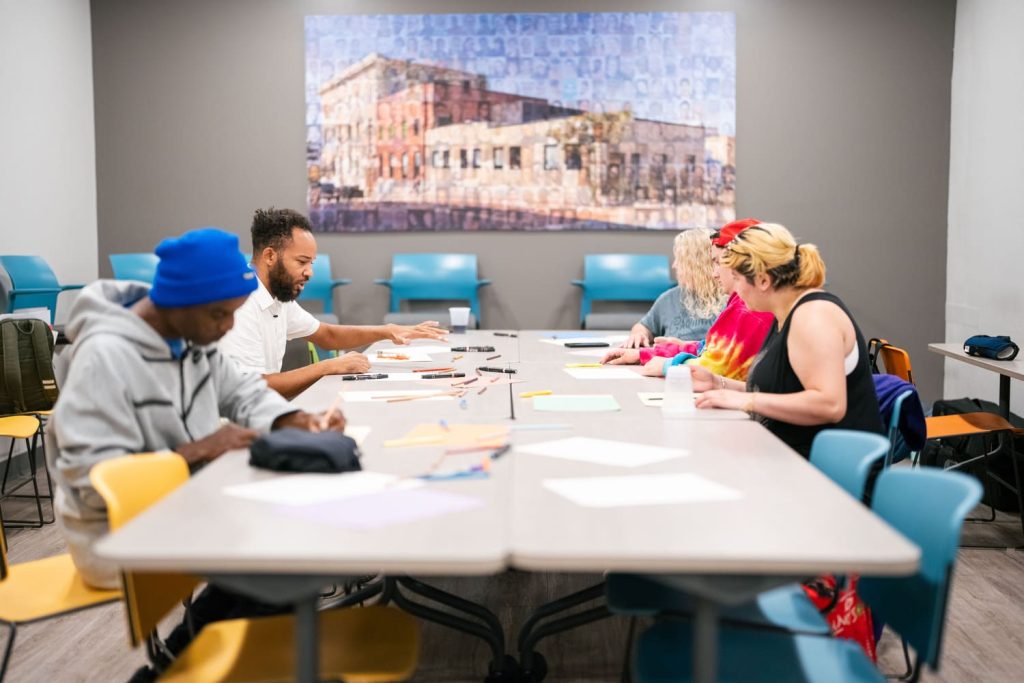 A collection of 4 people sitting around a conference table, clearly absorbed in their work and actively participating in discussion